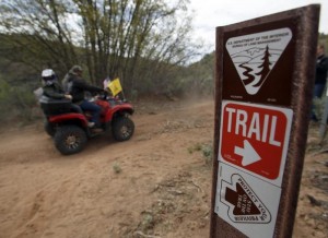 ATV riders ride past a trail sign in Recapture Canyon outside Blanding