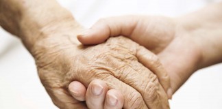 adult helping senior in hospital