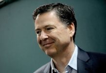 Smiling man in a dark blazer and light shirt, looking slightly to the right (profile portrait).”,