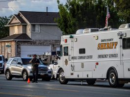 2nd man arrested after May 30 West Point homicide Davis County Sheriff mobile command center vehicle parked on a city street beside a cone and several cars, with a two-story house in the background and people nearby.