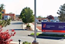 Intermountain Health Cedar City Hospital sign in a parking lot with trees and a hospital entrance in the background.