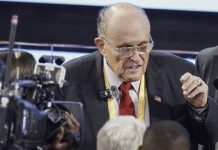 Former NYC-mayor Rudy Giuliani hospitalized in critical condition Older man in a suit and red tie speaks to reporters amid cameras and microphones at a press event.