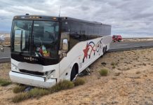 Motorcyclist dead after Kane County collision with tour bus White Van Hool tour bus stuck in sandy desert beside a highway, front wheels buried in sand with damage to bumper and grill.