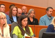 Group of people seated in a wood-paneled courtroom or hearing room; foreground includes a blonde woman in a cream blazer left, a woman in lime green center, and a blonde woman in blue right.