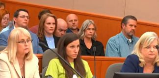 Group of people seated in a wood-paneled courtroom or hearing room; foreground includes a blonde woman in a cream blazer left, a woman in lime green center, and a blonde woman in blue right.