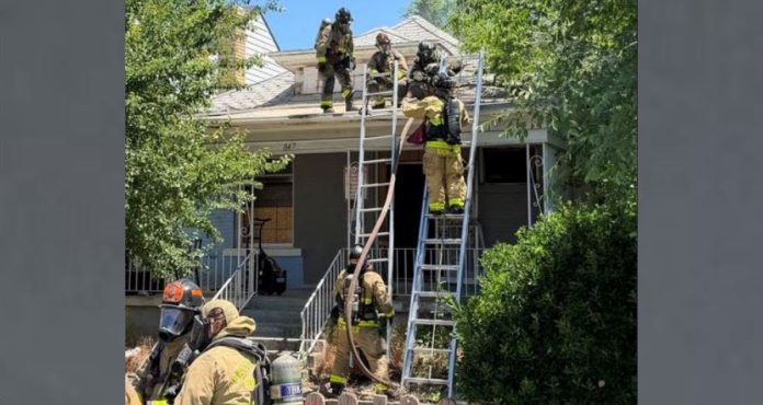 SL Fire Firefighters on ladders at the roof peak of a suburban home during an emergency response.