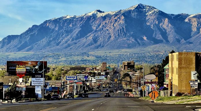 Anago Cleaning Ogden Layton Clearfield Wide city street with cars and billboards, mountains in the distance under a blue sky.