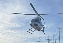 Motorcyclist flown to hospital in critical condition after Kaysville crash White helicopter hovering above power lines against a blue sky.