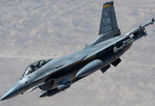 Fighter jet in flight with missiles mounted under the wings and tail code SW 226 against a desert backdrop