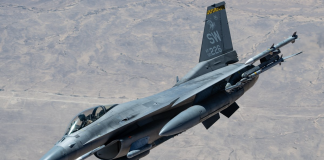 Fighter jet in flight with missiles mounted under the wings and tail code SW 226 against a desert backdrop