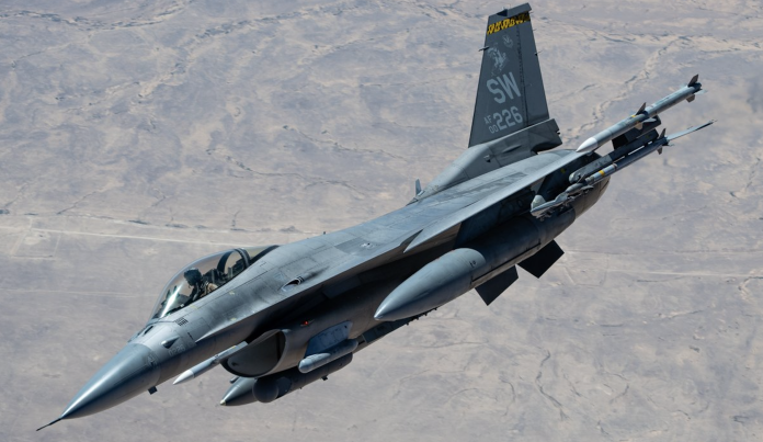 Fighter jet in flight with missiles mounted under the wings and tail code SW 226 against a desert backdrop