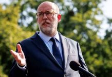 Trump administration wants all federal workers to sign NDAs Man in a navy suit and tie speaks at an outdoor podium with a microphone, gesturing with his left hand behind a backdrop of trees. (informative)
