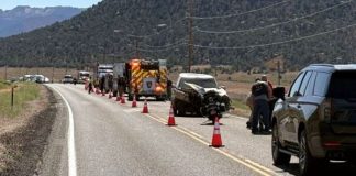 Emergency responders and vehicles on a highway scene with orange traffic cones around a motorcycle crash.