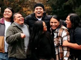 Group of six diverse friends outdoors in autumn, smiling and laughing together.