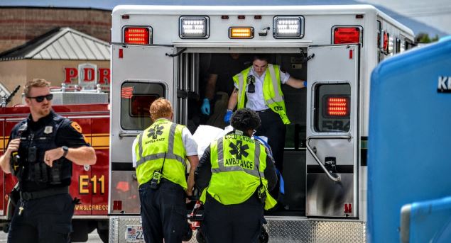 Paramedics load a patient into an ambulance while a police officer stands nearby.