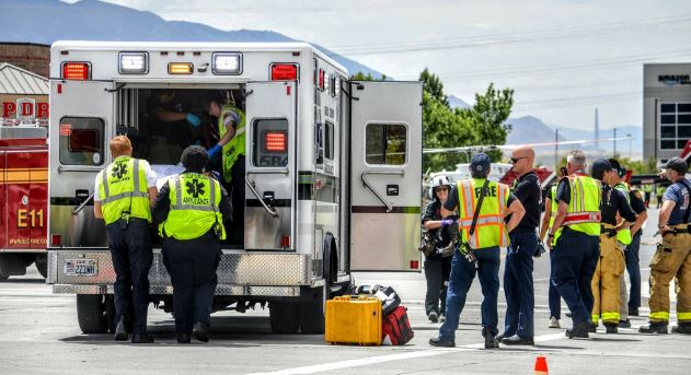 Emergency responders in reflective vests gather around an open ambulance, preparing equipment on a scene far from home.