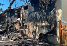 Unified Fire battles residential blaze in Magna Severely fire-damaged house with blackened walls, charred debris scattered in the front yard, and a wooden fence to the right.