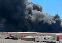 60 firefighters battle 3-alarm blaze at Salt Lake City recycling operation Large dark smoke plume rising from a warehouse district, with trucks and storage buildings in the foreground.