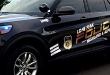 Black police SUV with LPD markings and Lone Peak Highland & Alpine decals, blue light visible on the front fender edge.