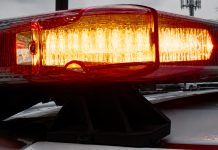 Close-up of a red and amber police vehicle light bar flashing on a patrol car roof ahead of snowy background.