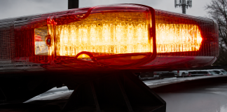 Close-up of a red and amber police vehicle light bar flashing on a patrol car roof ahead of snowy background.