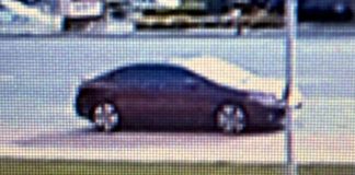 Side profile of a dark sedan parked on a street, viewed from the curb side in daylight
