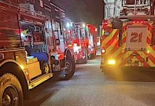 Nighttime street scene with multiple fire engines and flashing red and yellow emergency lights.