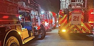 Nighttime street scene with multiple fire engines and flashing red and yellow emergency lights.