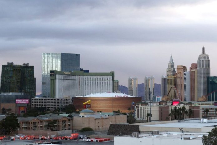 Las Vegas skyline featuring the Park MGM and nearby arena with surrounding hotels and high rises under a cloudy sky.
