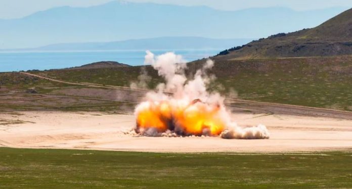 Hill AFB detonation Explosion in a barren landscape with orange flames and white smoke rising from ground blast site, hills in background.