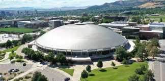 Aerial view of a large circular silver-domed building on a university campus with surrounding green lawns and parking lots.