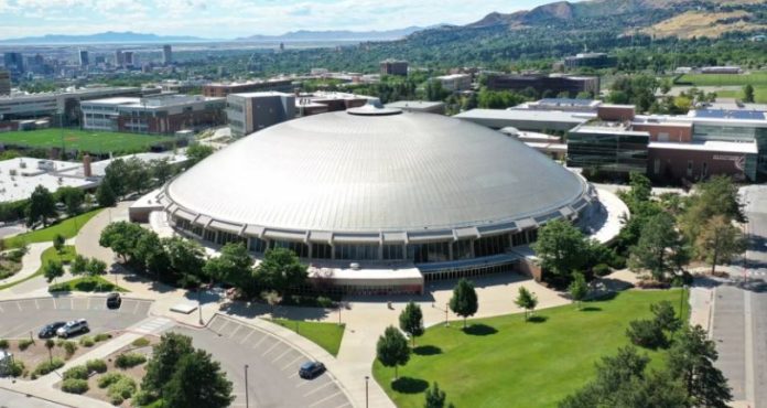 Aerial view of a large circular silver-domed building on a university campus with surrounding green lawns and parking lots.