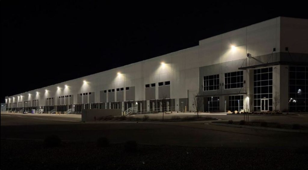 ICE-1024x565-1 | Gephardt Daily Nighttime exterior of a large warehouse with illuminated loading bays along its long facade.