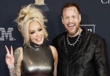 Jelly Roll divorcing Bunnie XO after 10 years of marriage Smiling blonde woman in a shiny sleeveless dress makes a peace sign beside a tattooed man in a black patterned jacket at an awards event.