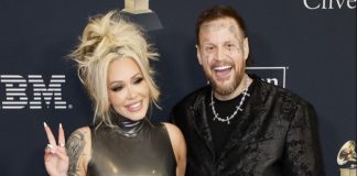 Jelly Roll divorcing Bunnie XO after 10 years of marriage Smiling blonde woman in a shiny sleeveless dress makes a peace sign beside a tattooed man in a black patterned jacket at an awards event.