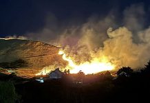 Update: Firefighters battle 200 acre Bonneville Fire near University of Utah, zero percent contained Nighttime wildfire on a hillside with bright flames, smoke rising above a small residential area.