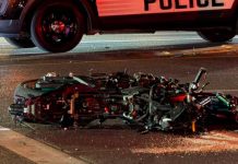 Motorcyclist suffers ‘significant’ injuries after hit by 2 cars near State Street and 2100 South Motorcycle wreck on a street, laid on its side with debris; a police vehicle looms over the scene with flashing lights in the background.