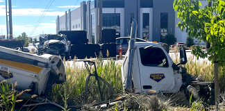 Abandoned Geneva Rock construction trucks in a grassy lot with a modern office building behind them.