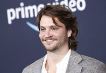 Season 2 of Luke Grimes’ ‘Marshals’ now filming in Park City Smiling man with medium-length brown hair and light beard wearing a gray blazer and white shirt at a Prime Video event.