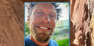 Close-up portrait of a smiling man with a light beard outdoors.