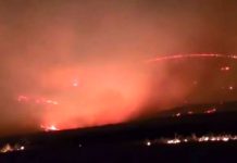 South Mountain Fire estimated at 1K-2K acres Nighttime wildfire along a ridge with flames and smoke lighting the sky.