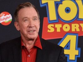 Smiling man in a red shirt and black blazer standing in front of a Toy Story 4 backdrop with a Babybel logo visible on the left.