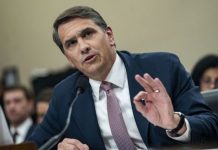 Trump administration seeking to denaturalize 17 over offenses Man in a blue suit speaks into a microphone during a formal hearing, gesturing with his right hand.