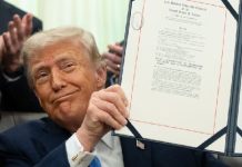 Donald Trump holding a framed certificate, smiling at the camera.