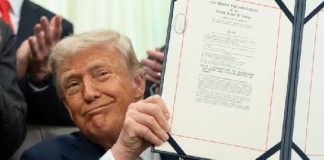 Donald Trump holding a framed certificate, smiling at the camera.