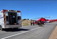 One person dead after NB I-15 collision in Juab County Ambulance with open rear doors on a rural highway, as medical crew load a red helicopter ambulance on the road shoulder for airlift.