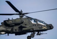 U.S. helicopter crew rescued after coming down near Strait of Hormuz AH-64 Apache attack helicopter in flight, with landing gear visible and weapons mounted under the fuselage.