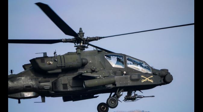 US-helicopter-crew-rescued-after-coming-down-near-Strait-of-Hormuz AH-64 Apache attack helicopter in flight, with landing gear visible and weapons mounted under the fuselage.