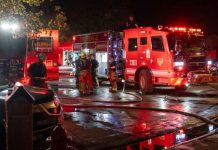Unified Fire knocks down Taylorsville house fire Firefighters and red fire trucks at night, hoses on the wet street preparing for operation.