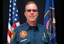 Provo Fire & Rescue announces death of Captain Spencer Long, 4 family members killed in flash flood Male emergency services officer in a teal uniform with patches, posed in front of U.S. and state flags behind him.